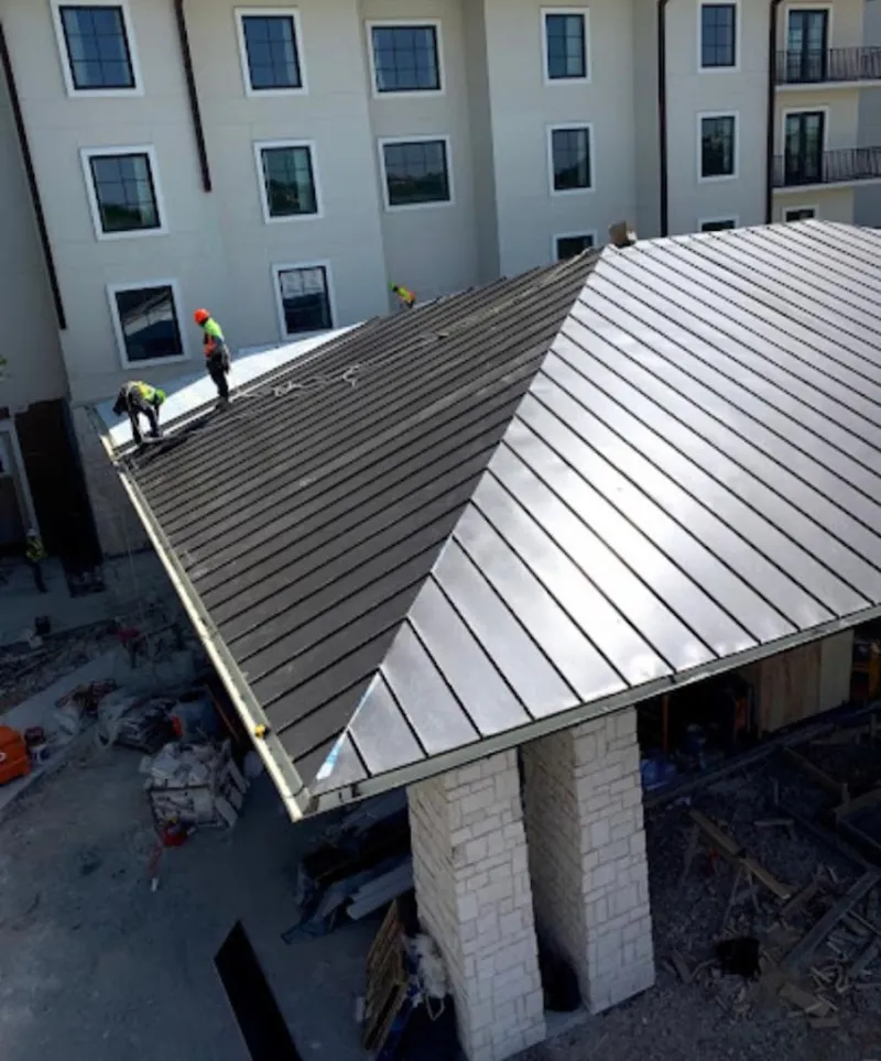 Crew installing standing seam metal roof panels on a commercial project in Marengo